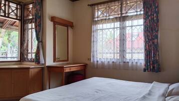 Un dormitorio con cama, cómoda de madera, una mesita y un espejo.
