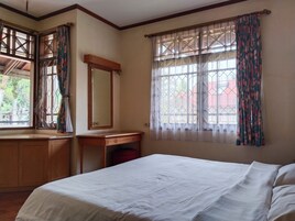 Un dormitorio con cama, cómoda de madera, una mesita y un espejo.
