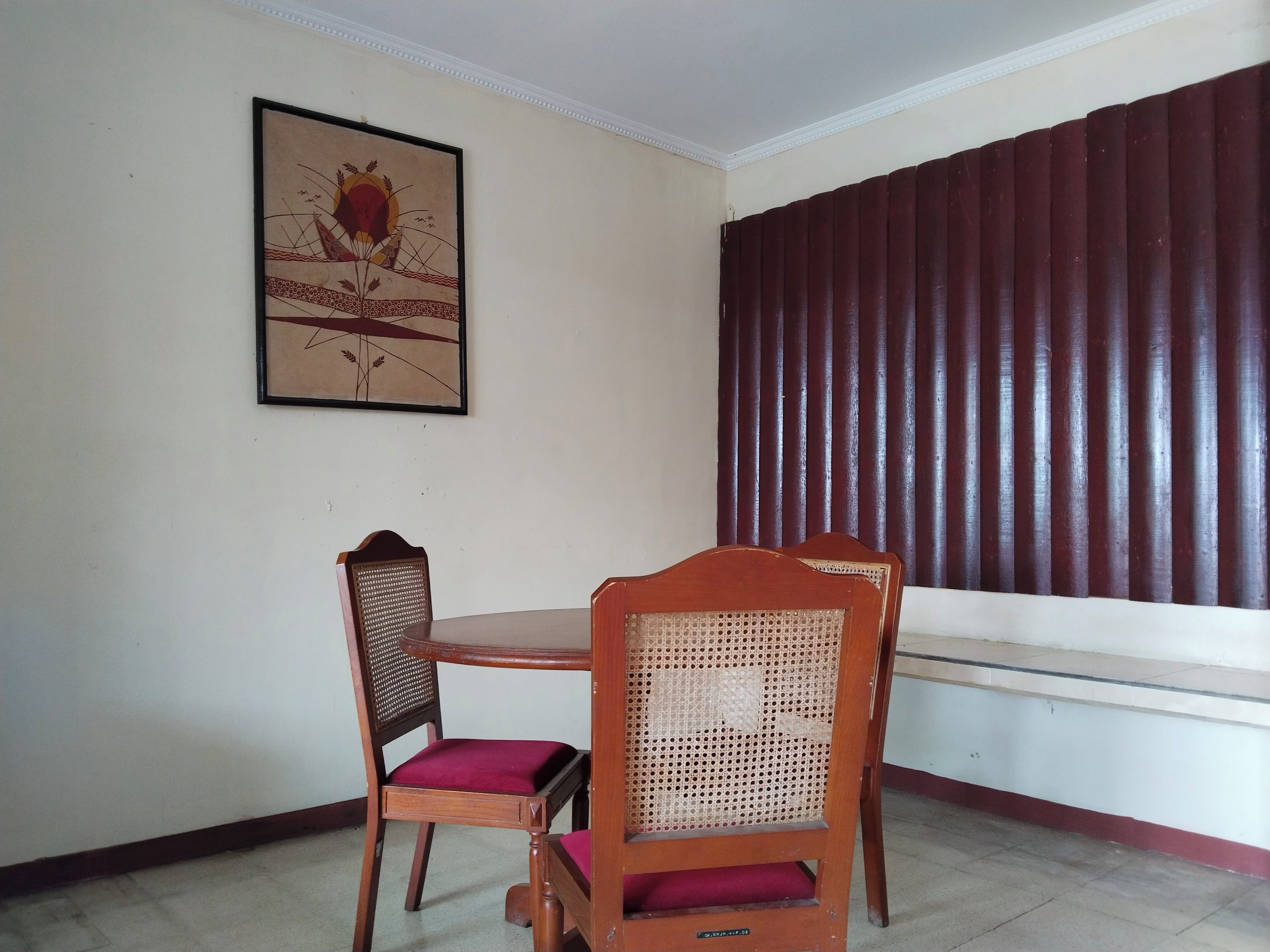Un comedor con una mesa y sillas, un cuadro en la pared y un ventanal con persianas verticales.