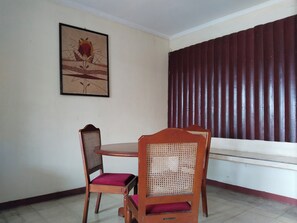Un comedor con una mesa y sillas, un cuadro en la pared y un ventanal con persianas verticales.