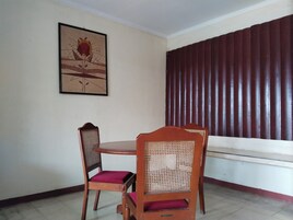 Un comedor con una mesa y sillas, un cuadro en la pared y un ventanal con persianas verticales.