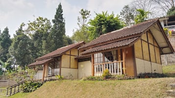 Uma casa tradicional com telhado de telhas, fachada de madeira e pequena varanda com corrimão.