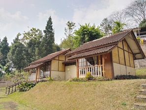 Une maison traditionnelle avec un toit en tuiles, une façade en bois et un petit porche doté d’une balustrade.