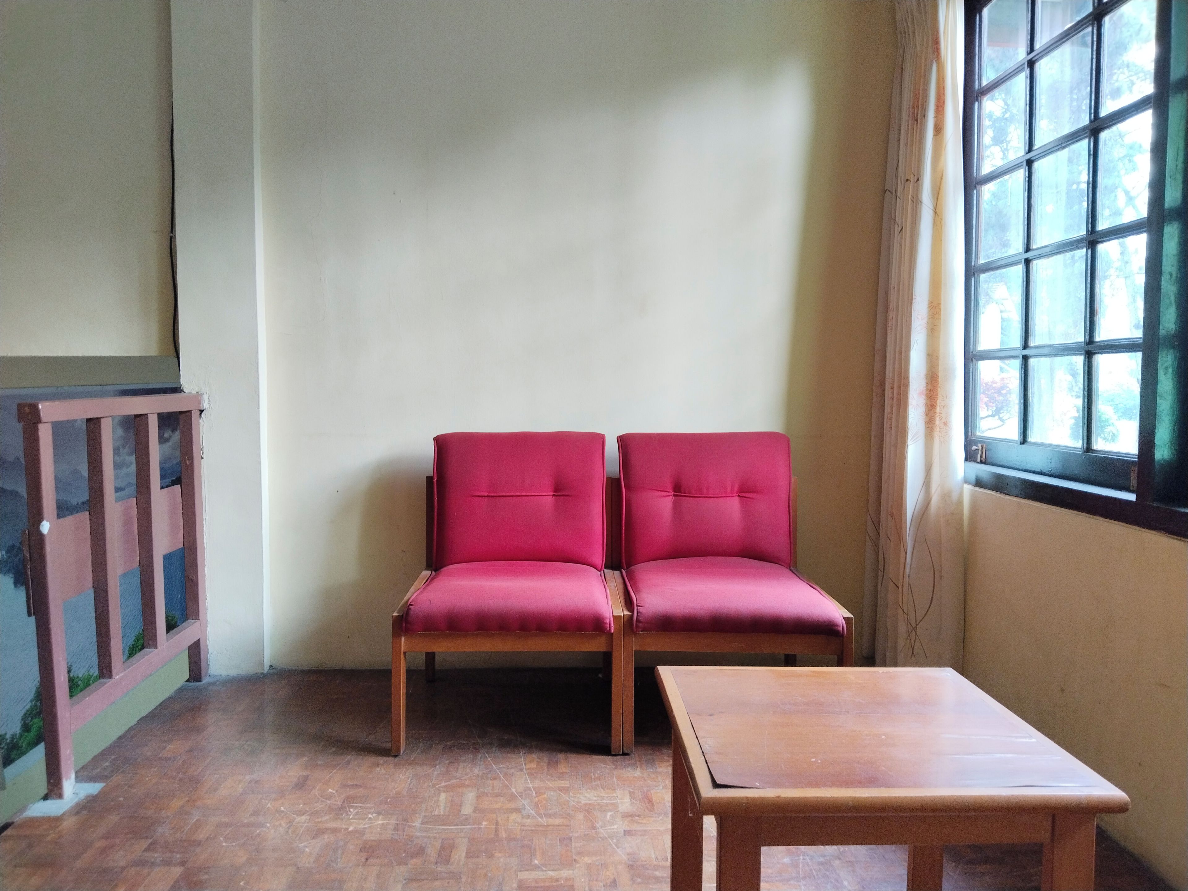 Una habitación con una mesa de madera y dos sillas rojas.