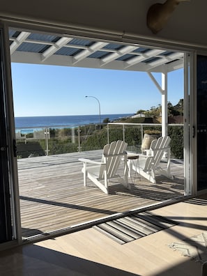 Een terras met twee Adirondack stoelen, uitzicht op de oceaan en een heldere lucht.