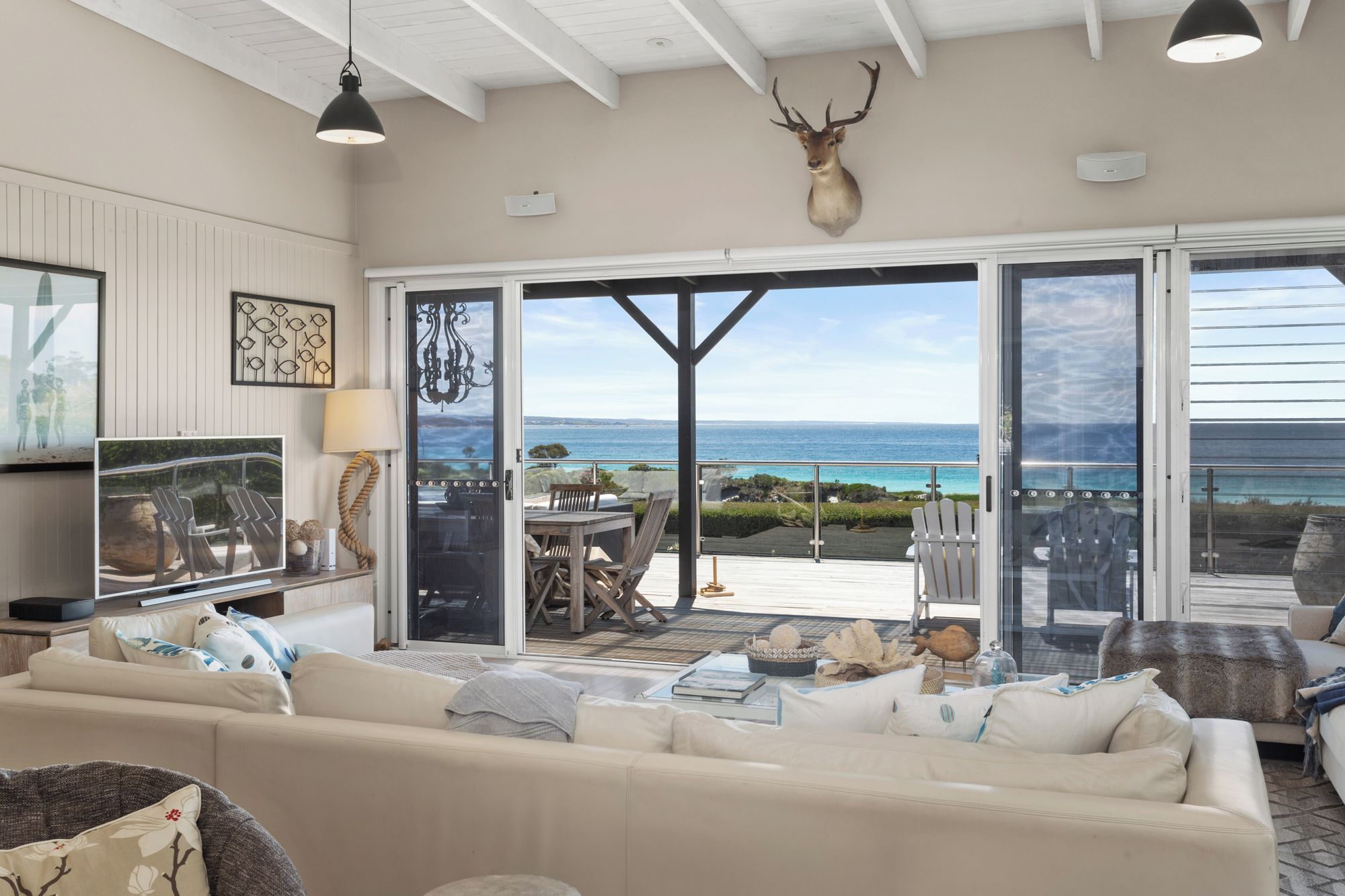 Een ruime woonkamer met een grote schuifpui naar een terras buiten met uitzicht op de oceaan.