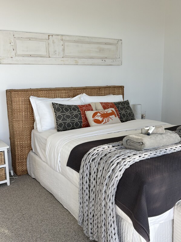 A bed with a woven headboard, white bedding, and decorative pillows.