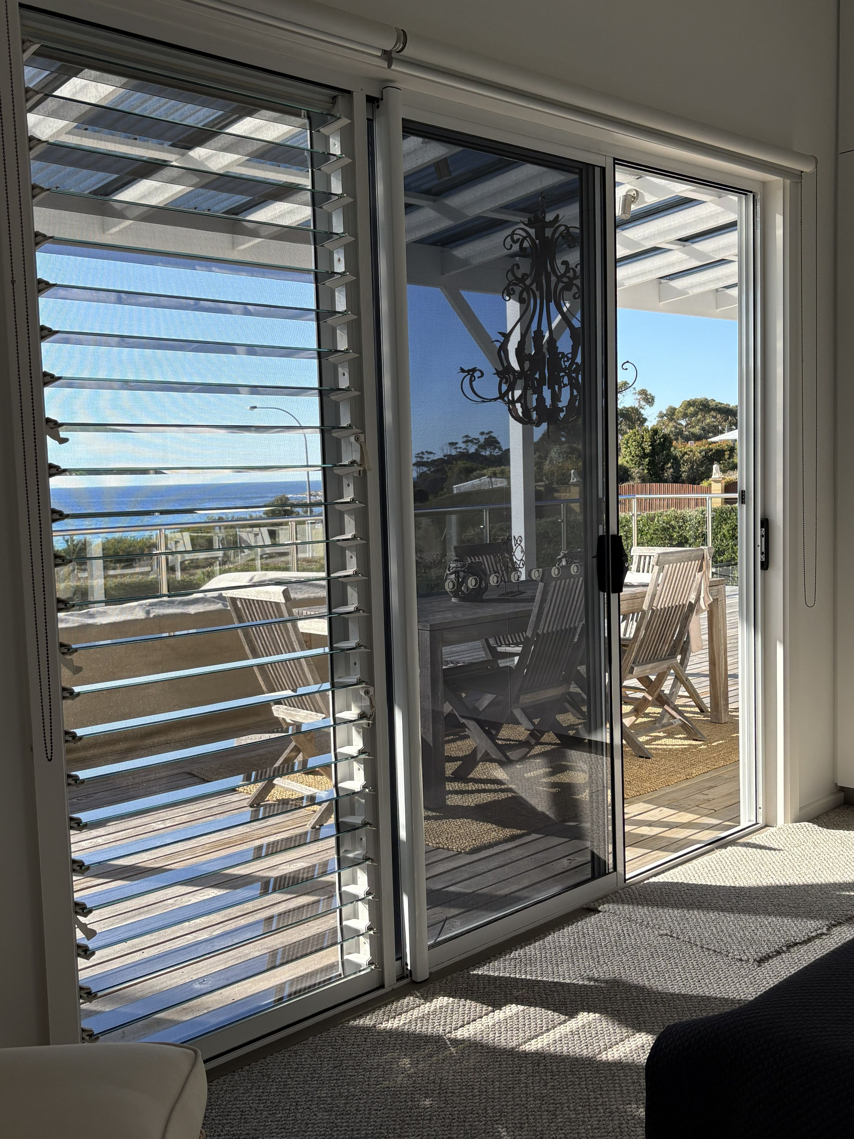 A sliding glass door leading to an outdoor patio with a view of the ocean.