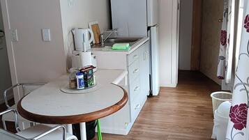 A compact kitchen with a microwave, refrigerator, and a sink. There is a clock on the wall and a sign with the word 'HOPE'.
