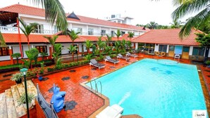 Ein Hotel mit Schwimmbad, Palmen und roten Ziegeldächern.