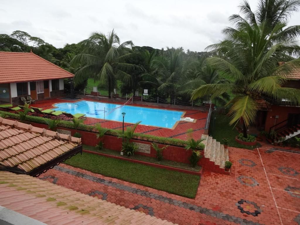 Una piscina rodeada de palmeras y un edificio con techo rojo.