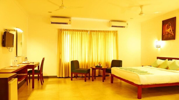 Een hotelkamer met een bed, een bureau, stoelen, een tafel en een airconditioner.