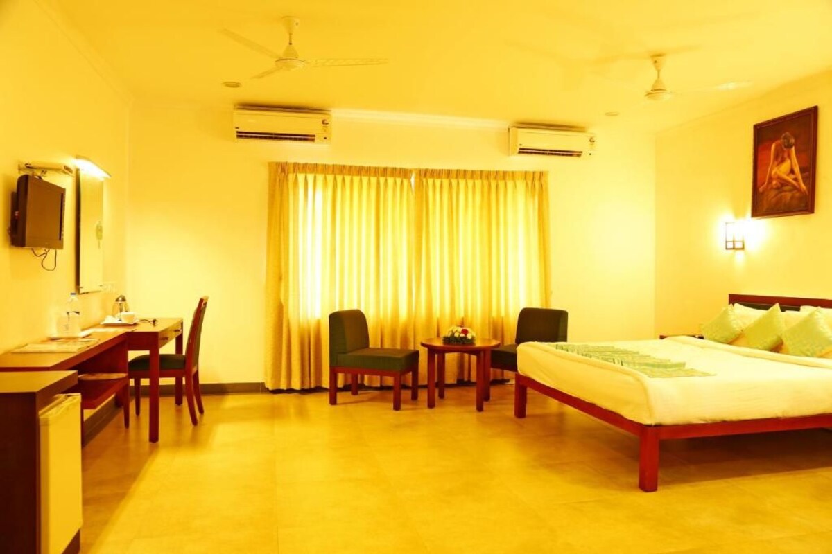 Een hotelkamer met een bed, een bureau, stoelen, een tafel en een airconditioner.