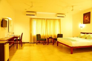 Habitación de hotel con cama, escritorio, sillas, una mesa y un aire acondicionado.