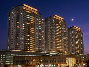 A high-rise hotel with multiple floors, illuminated windows, and a visible moon in the sky.