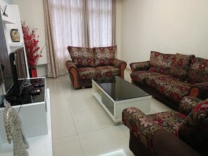 A living room with a sofa set, a coffee table, and a television on a stand.