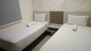 A hotel room with two single beds, a nightstand, and a wall-mounted TV.