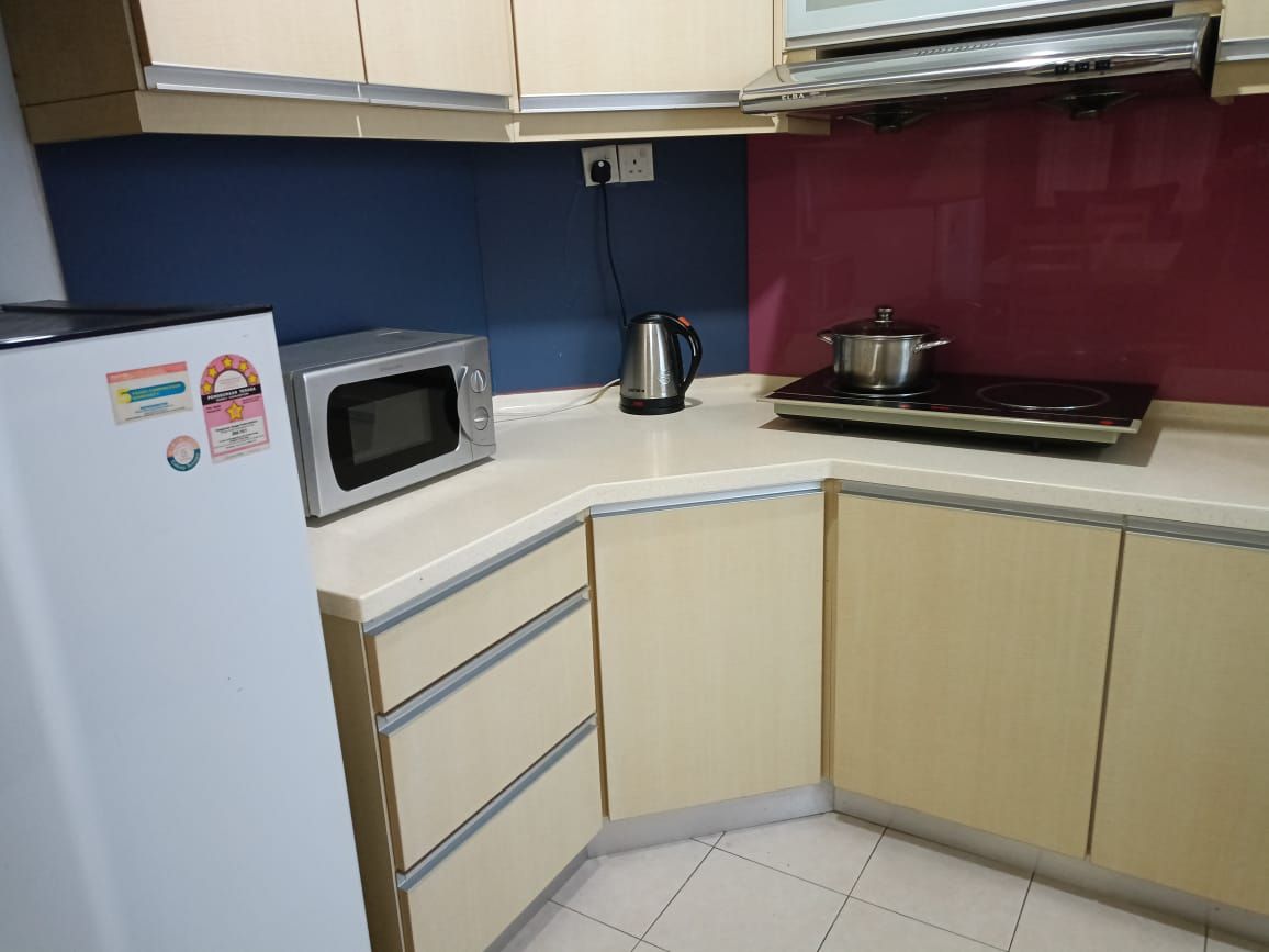 A kitchen with a microwave, kettle, and stove.