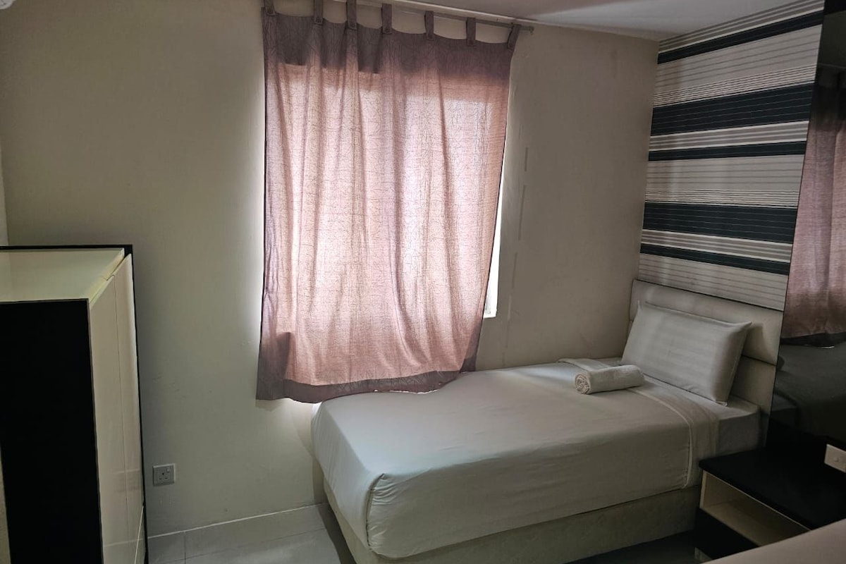 Una cama individual con una almohada, una mesita de noche, una ventana con cortinas y una pared con un estampado a rayas.