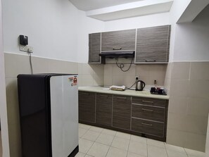 Una cocina compacta con nevera, microondas y cafetera en la encimera.