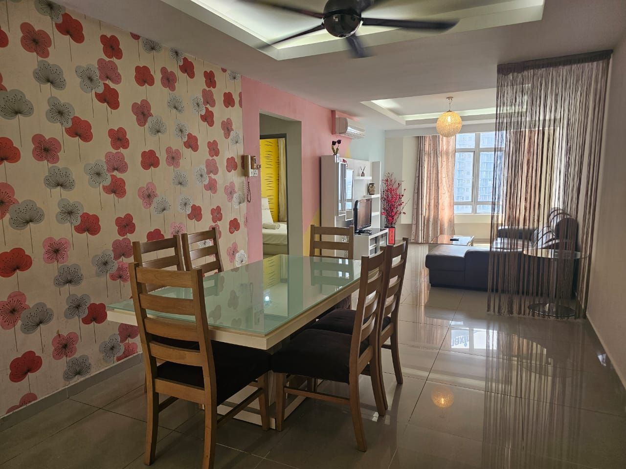 A dining area with a glass table, wooden chairs, and a patterned wall.