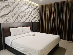 A hotel room with a large bed, a marble-patterned wall, and a curtain.