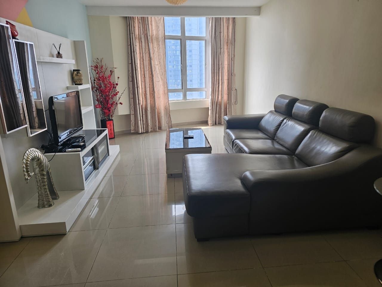 A modern living room with a sectional sofa, a flat-screen TV, and a coffee table.