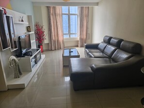 A modern living room with a sectional sofa, a flat-screen TV, and a coffee table. - Putra Majestik (Kuala Lumpur)