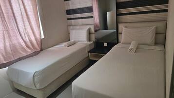 A room with two beds, a small table, and a mirror.