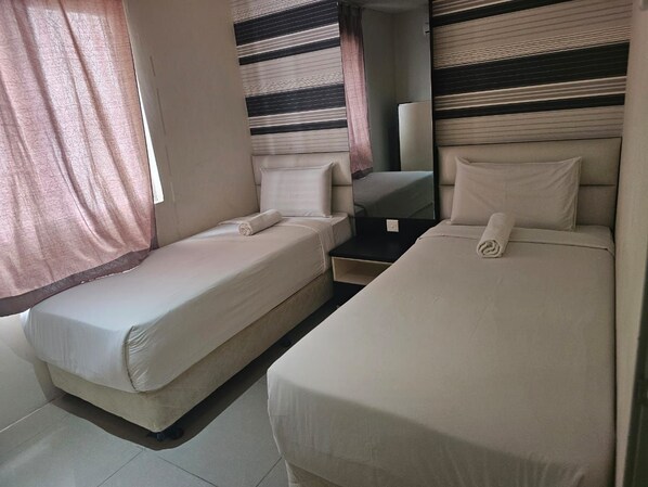 A room with two beds, a small table, and a mirror. - Putra Majestik (Kuala Lumpur)