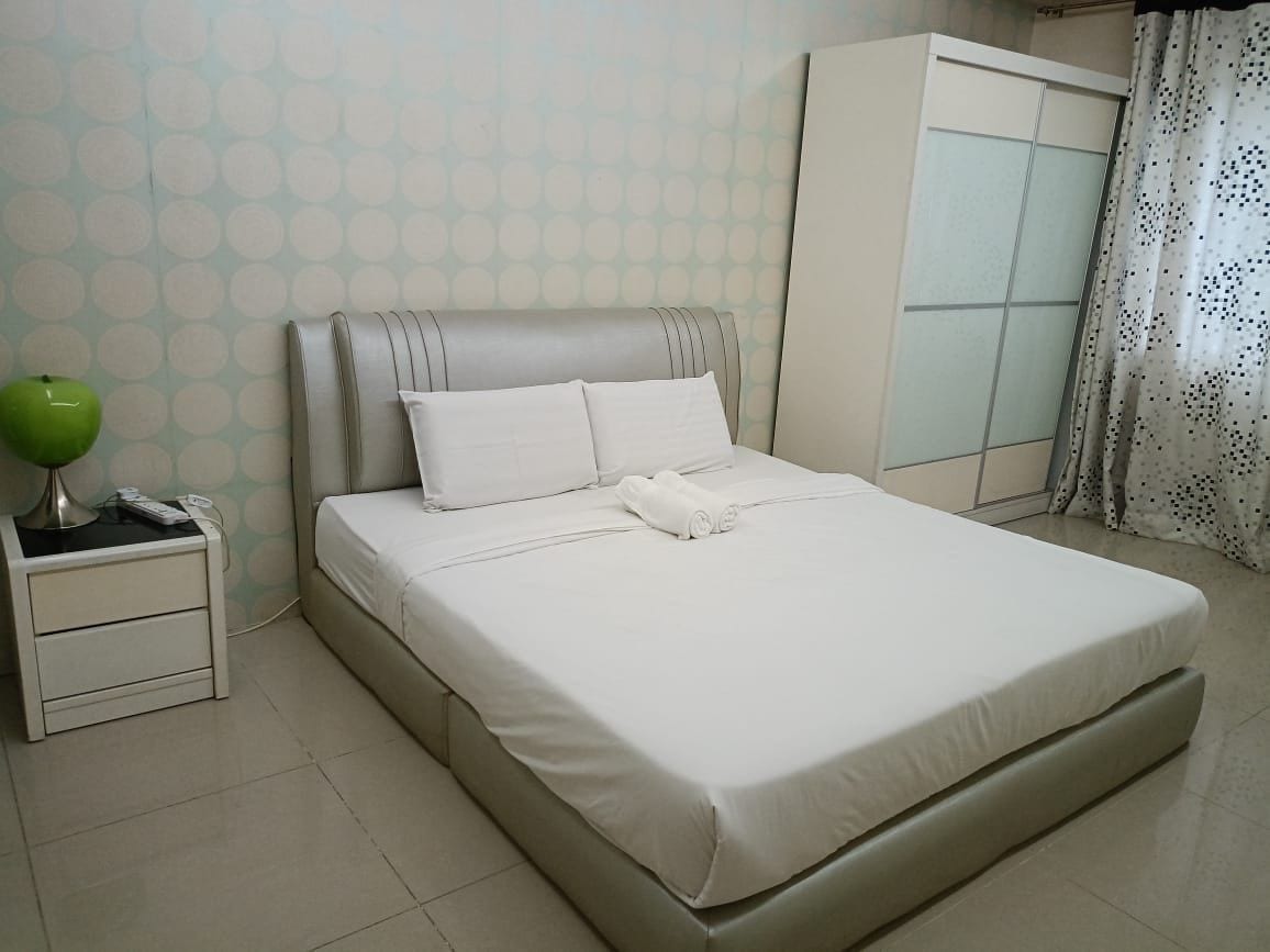A neatly made bed with white bedding, a bedside lamp, and a wardrobe with a frosted glass door.