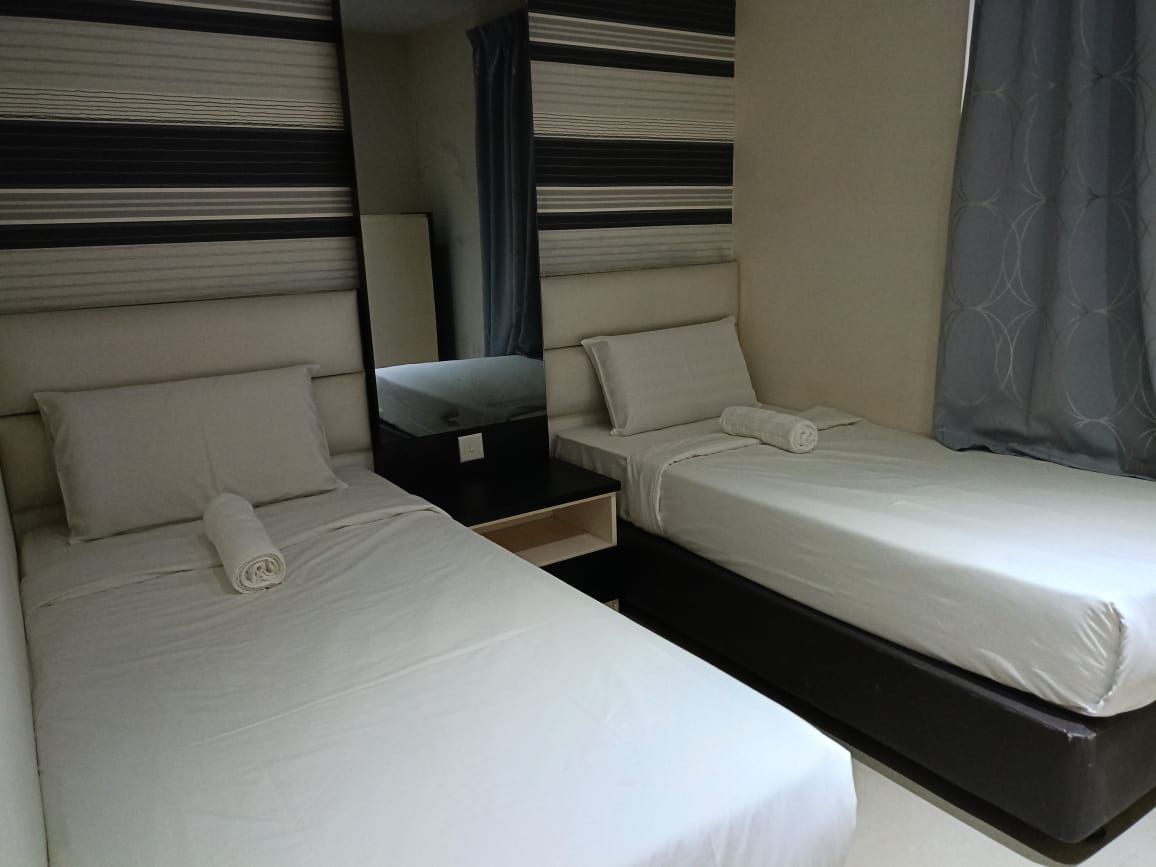A hotel room with two beds, a nightstand, and a mirror.