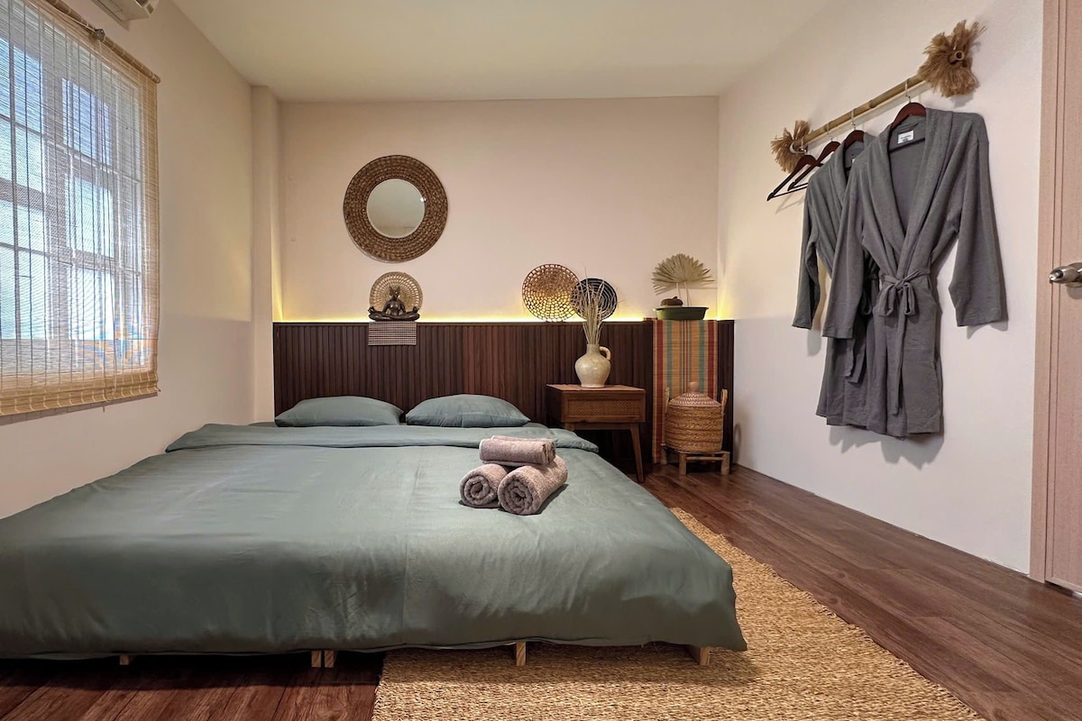 Ein Schlafzimmer mit Bett, Nachttisch, Spiegel und einem an der Wand hängenden Bademantel.