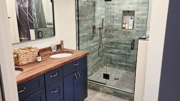 Un bagno con soffitto in legno, cabina doccia in vetro, lavabo con specchio e mobili scuri.