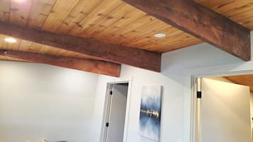 A room with a wooden ceiling, a white door, and a painting on the wall.
