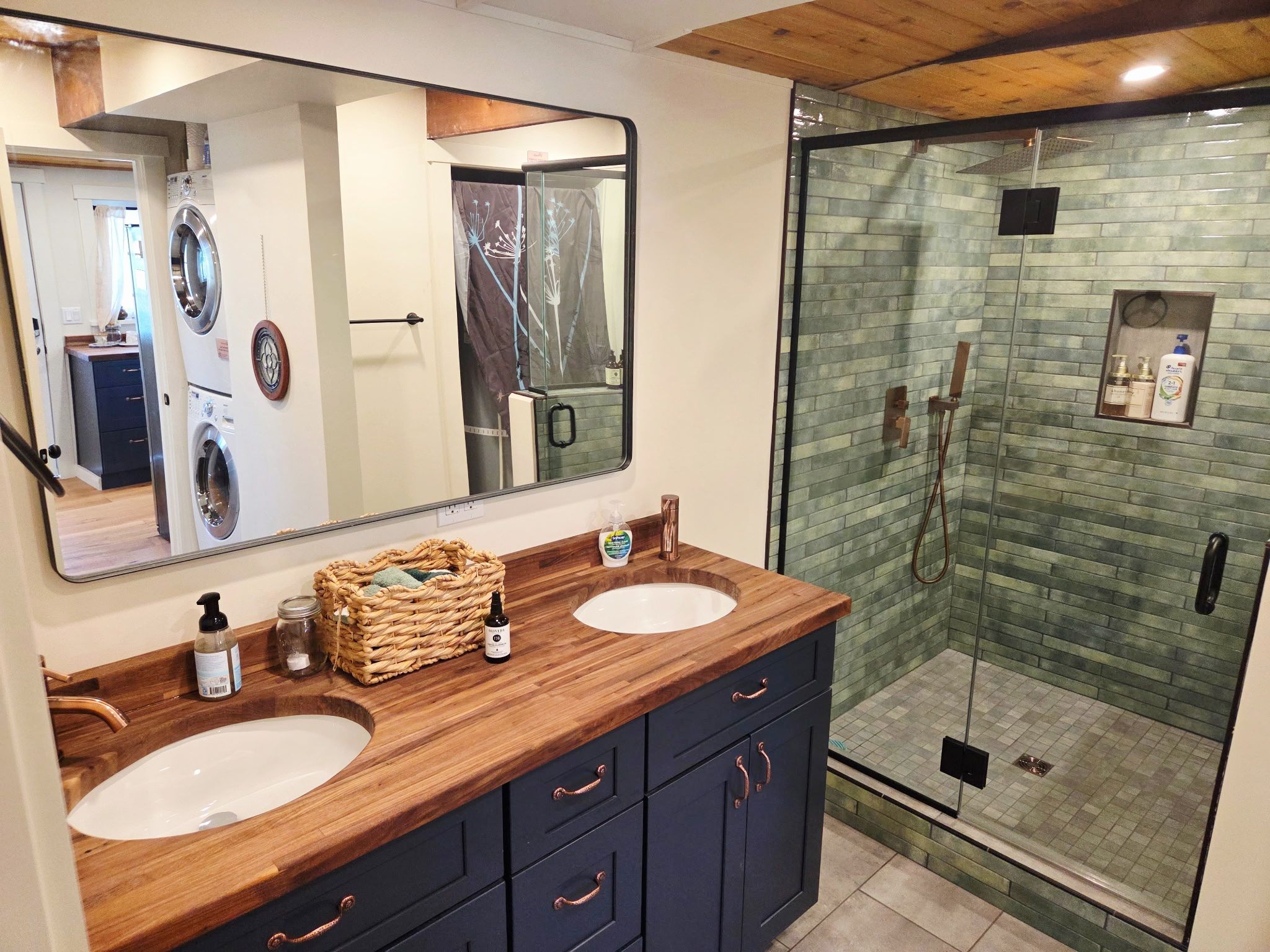 Un baño con dos lavamanos, un espejo grande, un mueble de tocador de madera y una ducha con mampara de vidrio.