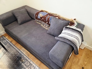 A grey sofa with a patterned throw blanket and a grey pillow.
