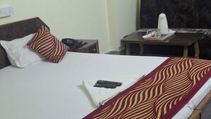 Quarto de hotel com cama, escrivaninha, cadeira, televisão e tomada.