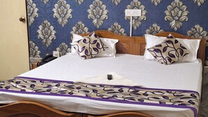 Quarto com cama, cabeceira de madeira, parede estampada, porta e chão de mármore.