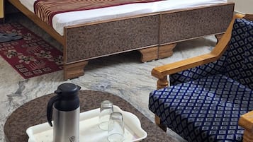 Habitació d'hotel amb llit, taula amb tetera i vasos, i una butaca amb dibuixos.