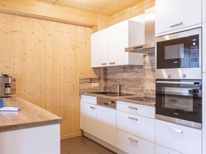Une cuisine moderne avec des armoires blanches, des appareils en acier inoxydable et un mur en bois.