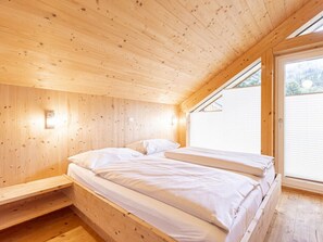 A wooden cabin room with a bed, a window, and a skylight. - One-bedroom Cabin (Sankt Georgen am Kreischberg)