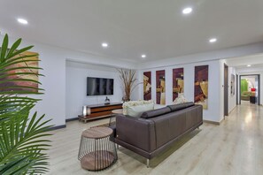 A modern living room with a sofa, a TV, and abstract art on the wall. - Pratumnak Hill Pool Villa 4BR (PH1) (Banglamung)