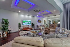 A modern living room with a large flat-screen TV, comfortable seating, and a decorative wall piece. - Pratumnak Hill Pool Villa 4BR (PH1) (Banglamung)