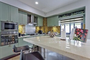 A modern kitchen with green cabinets, stainless steel appliances, and a large island. - Pratumnak Hill Pool Villa 4BR (PH1) (Banglamung)