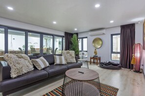 Een moderne woonkamer met een leren bank, een ronde salontafel en een groot raam met uitzicht op het landschap.