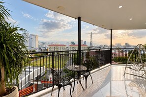 A balcony with a view of a cityscape, featuring a table and chairs, and a potted plant. - MT Danang Hotel - Near Dragon Bridge (An Hai)