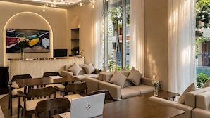 Ein modernes Wohnzimmer mit einer Couch, einem Esstisch und Stühlen, einem Laptop auf dem Tisch und einem Fernseher an der Wand.