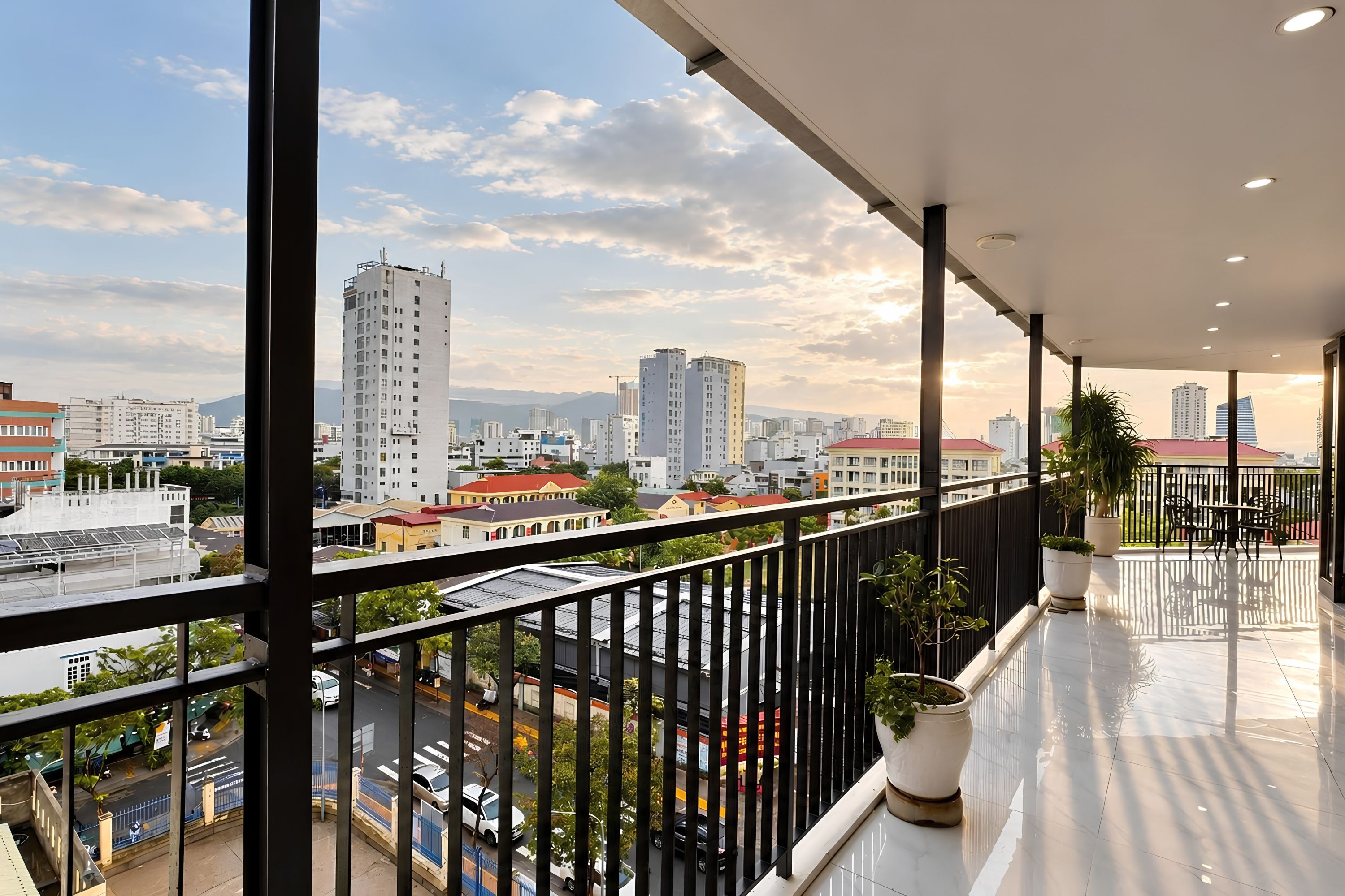 Un balcón con vistas a la ciudad, barandas de metal y plantas en macetas.