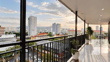 Un balcón con vistas a la ciudad, barandas de metal y plantas en macetas.